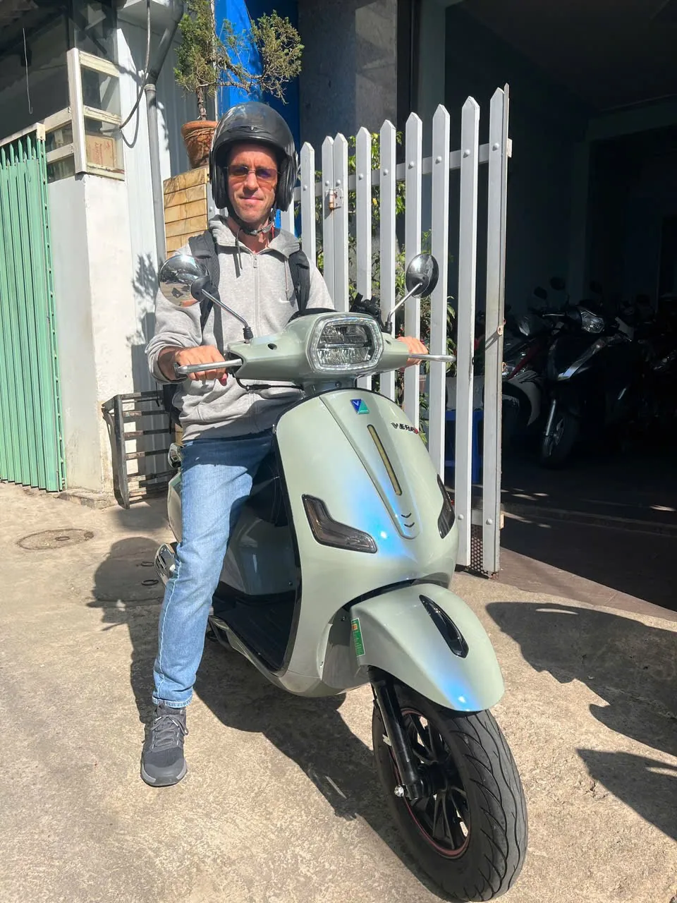 Smiling rider in a helmet on our pastel green 50cc scooter outside the Motorbike Dalat shop in Dalat