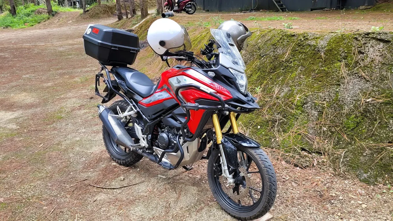 Red Honda CB150X parked in the pine forest near Dalat